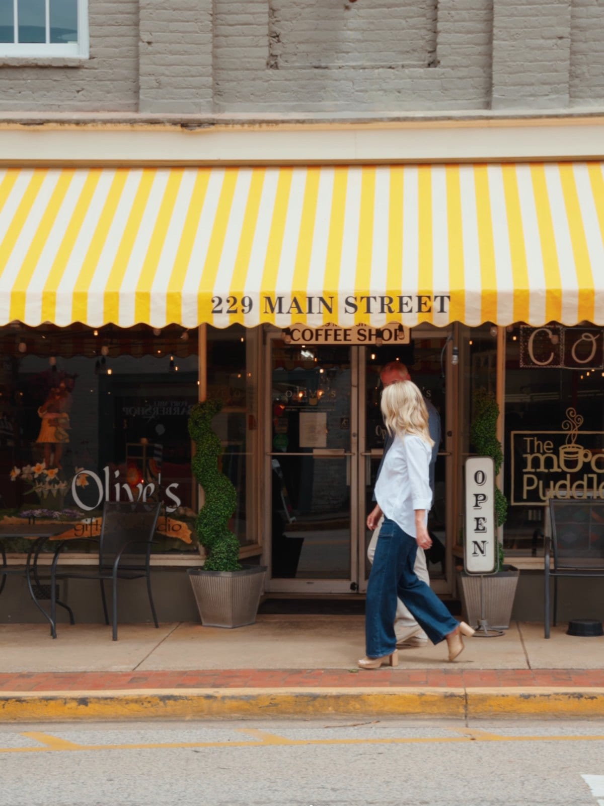 A coffee shop at 220 Main Street in Fort Mill, with a yellow striped awning and a passer-by on the sidewalk