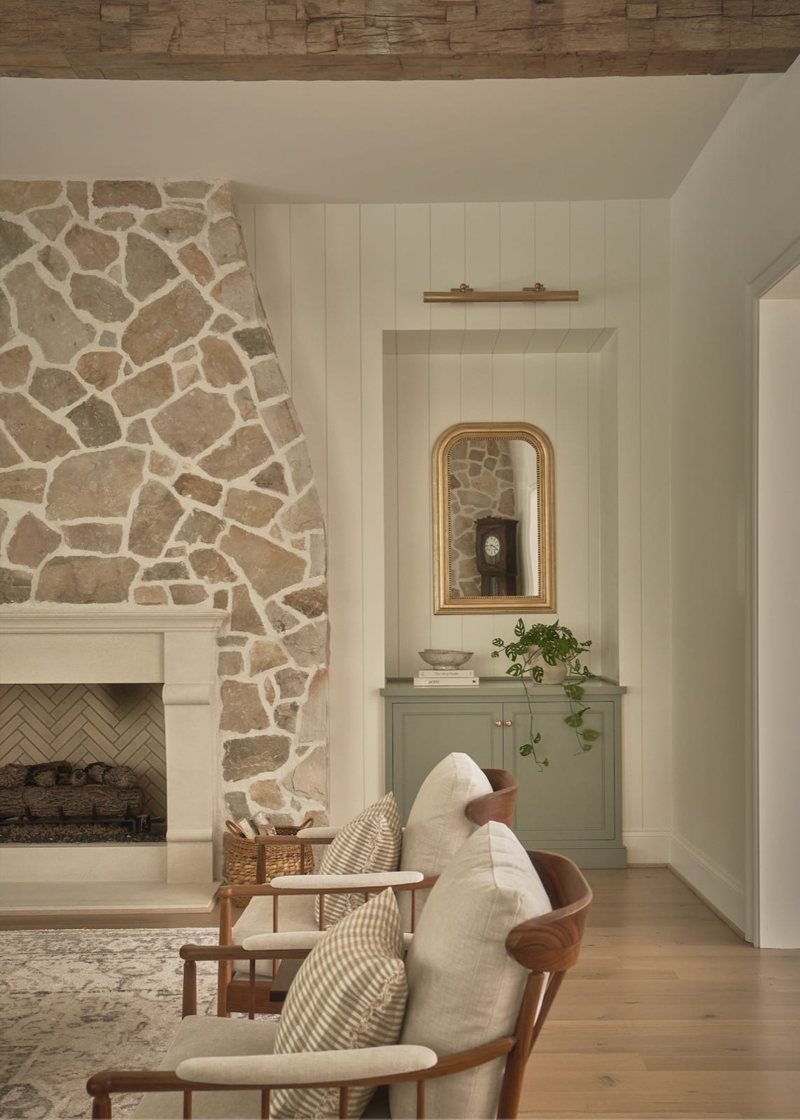 Living room at Meadowbrook Cottage with a floor-to-ceiling natural stone fireplace, an exposed beam and linen seating