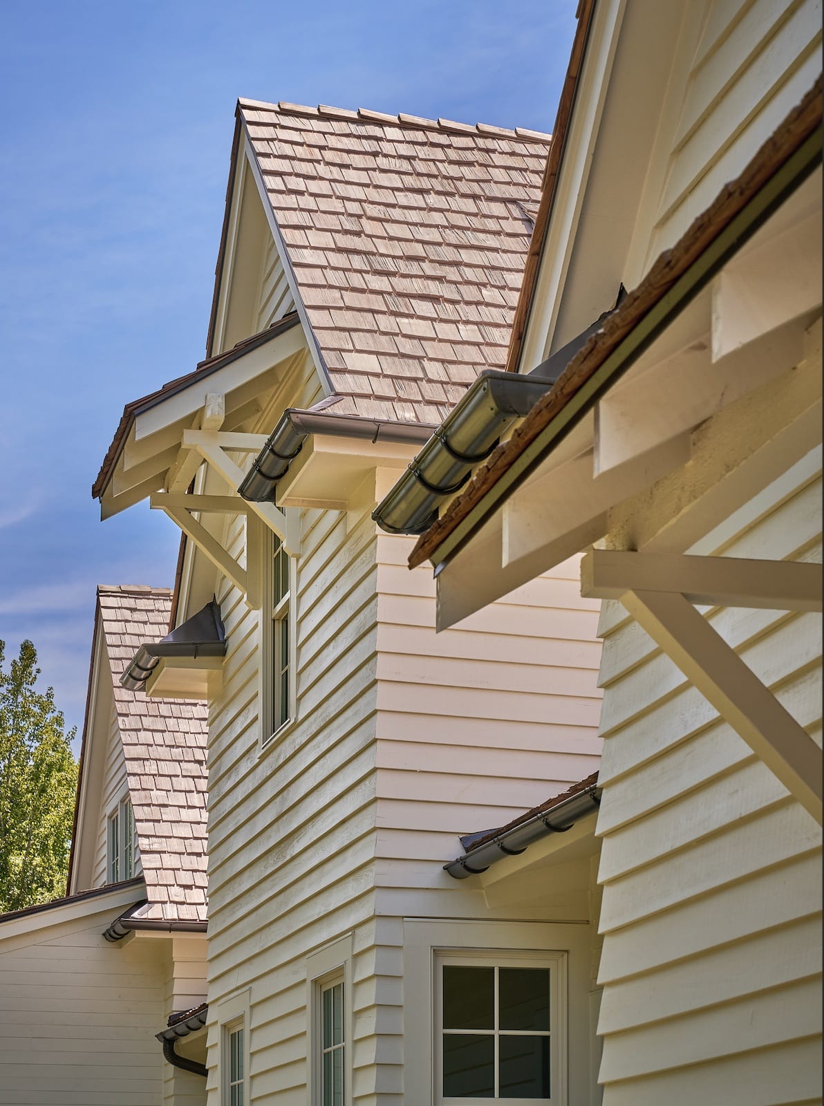 Cedar-shake rooflines and bracketed eaves of The Potter House against a clear sky