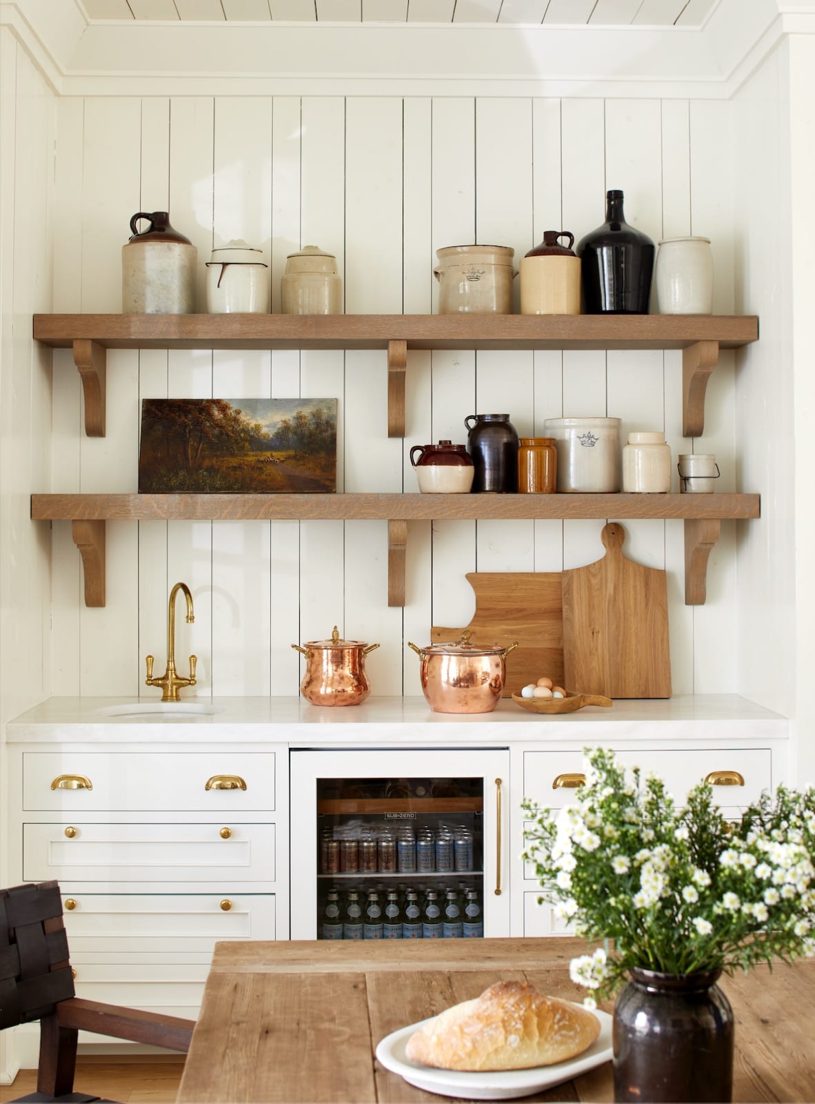 Scullery at The Potter House with open oak shelving, collected crockery, a brass faucet and a beverage refrigerator