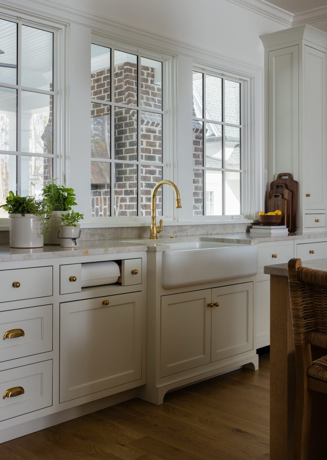 Kitchen at The Potter House with a farmhouse sink, brass faucet and windows framing a brick chimney