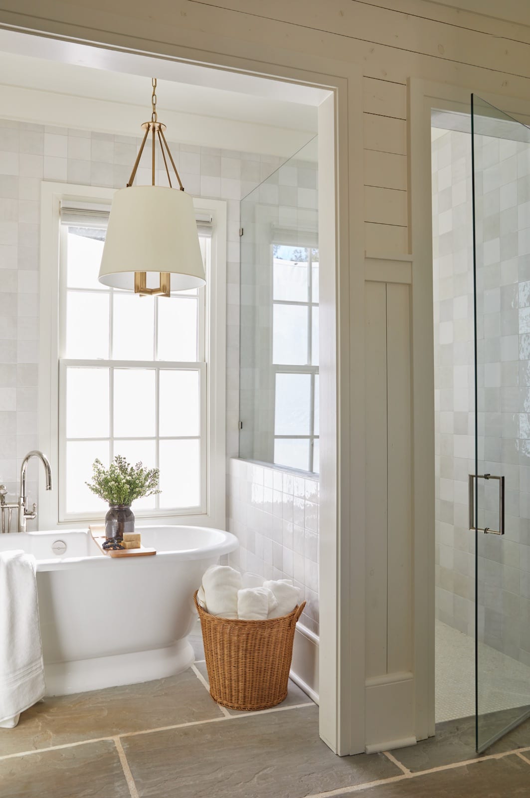 Primary bath at The Potter House with a freestanding tub, a tiled walk-in shower and a stone-tile floor