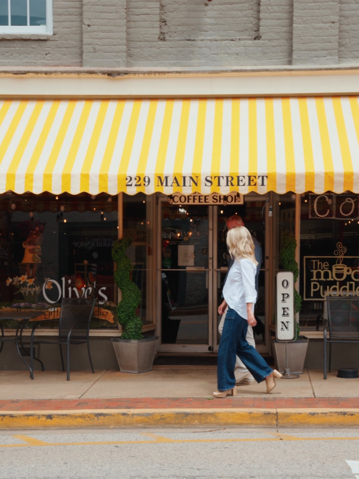 A storefront on Fort Mill's historic Main Street, with a striped awning and a passer-by on the sidewalk